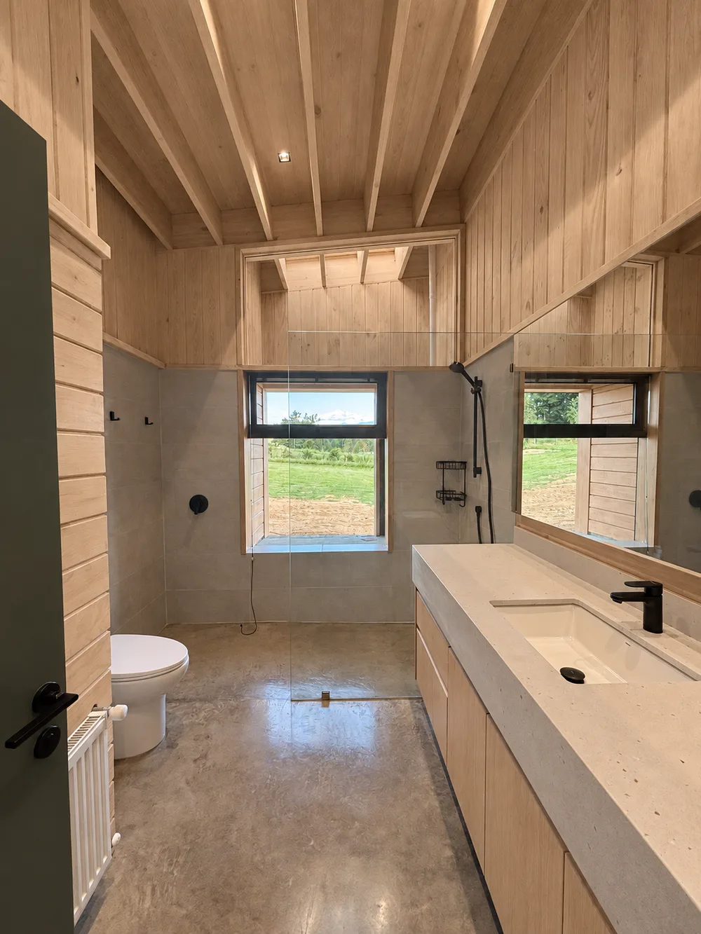 Casa Almares — baño principal revestido en madera con vista al paisaje