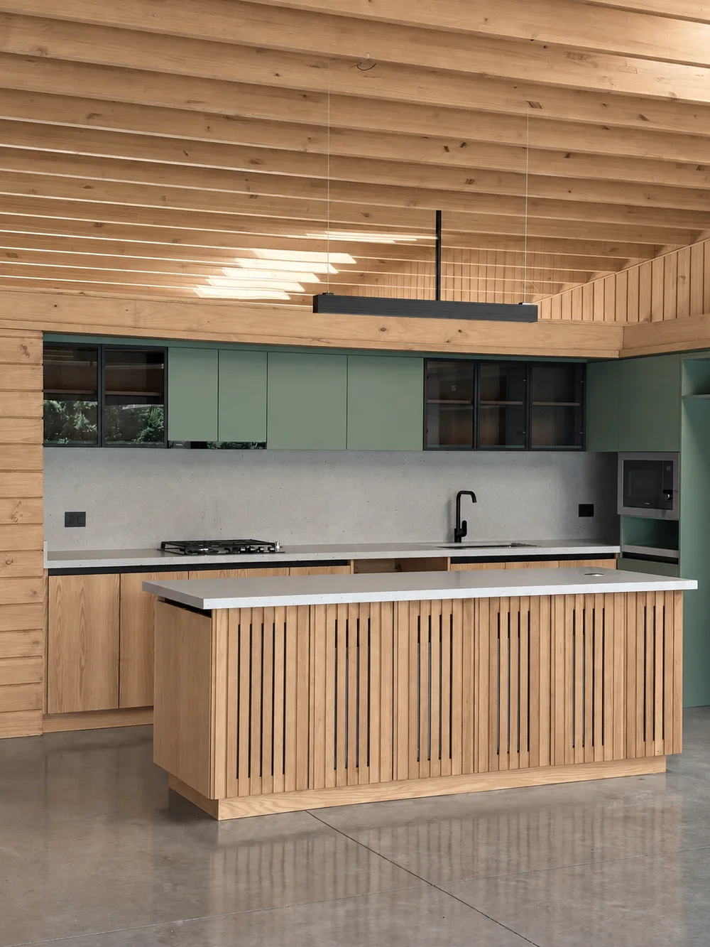 Casa Almares — cocina abierta con isla central y muebles verdes bajo el cielo de madera