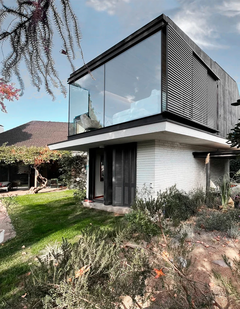 Casa Buenaventura — fachada posterior con jardín y volumen vidriado