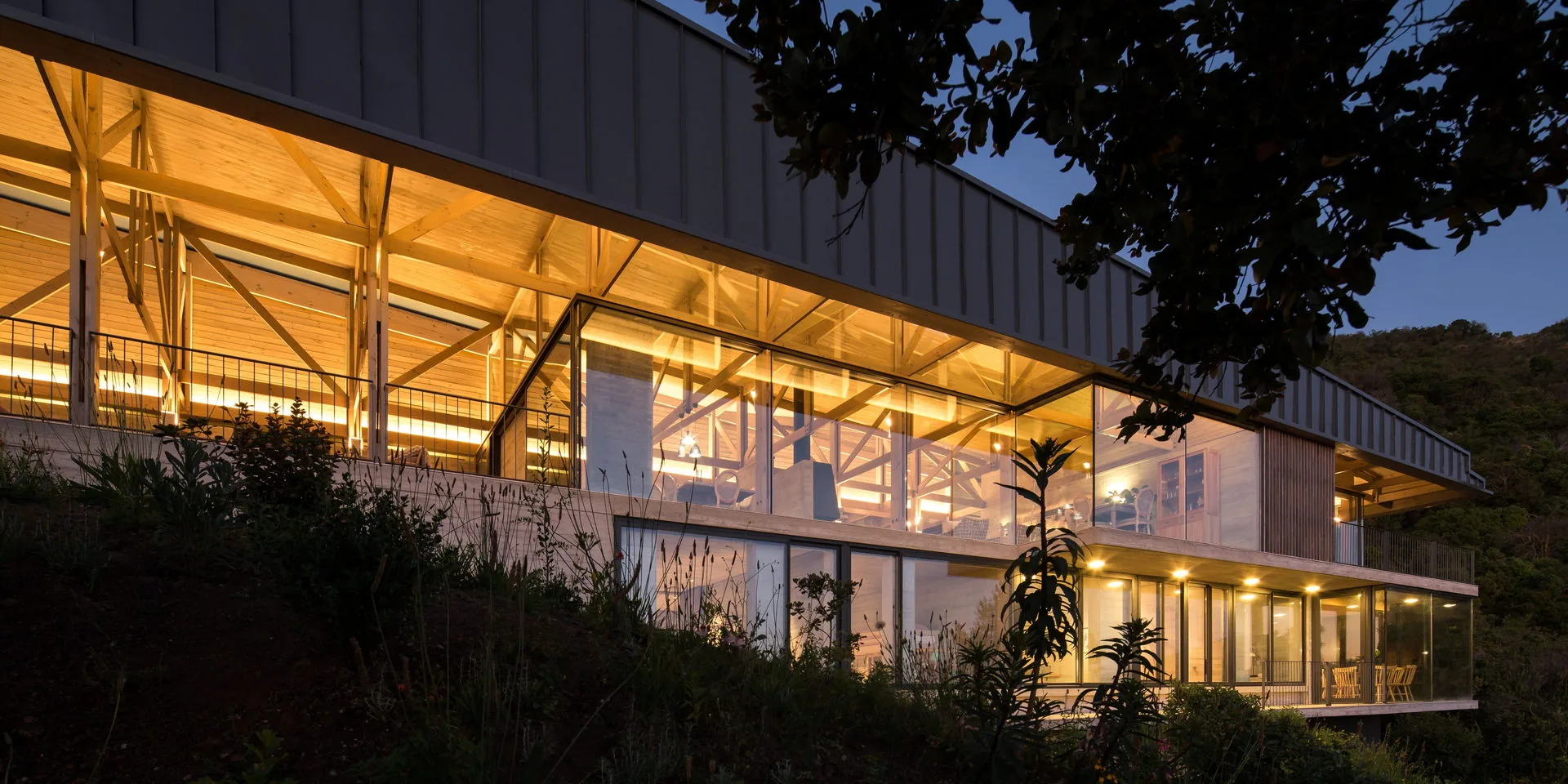 Casa 59, Cerro El Boldo — fachada nocturna iluminada con estructura de madera y vidrio