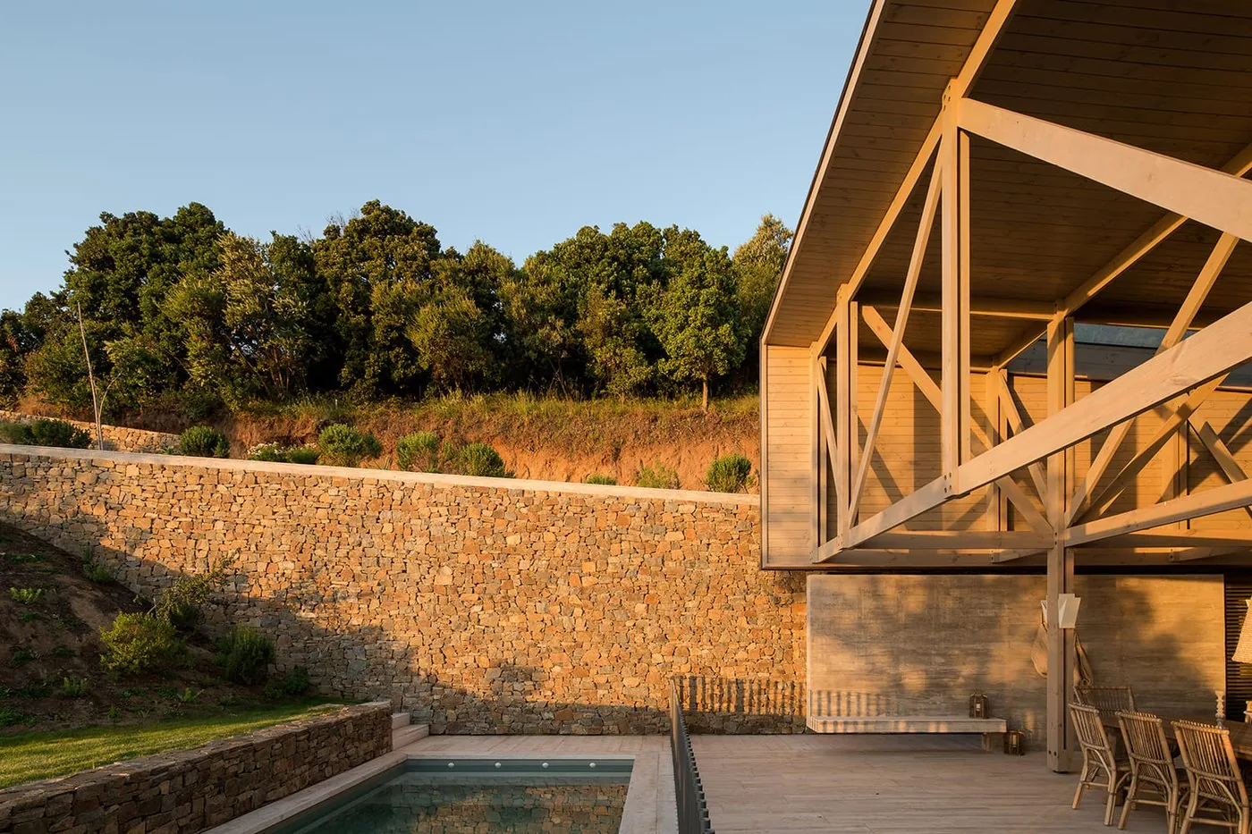 Casa 59 — terraza de piscina con muro de piedra y pérgola de madera