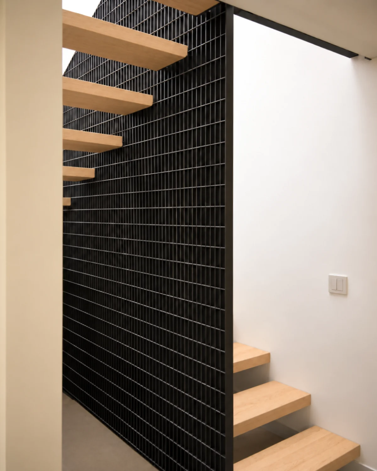 Casa Apolo — escalera de madera junto a celosía metálica negra