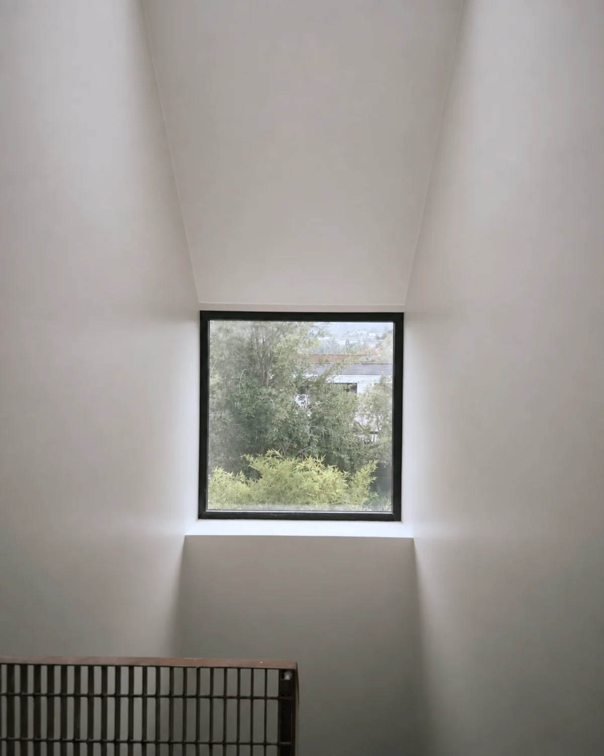 Casa Apolo — ventana cuadrada hacia el jardín en el hueco de la escalera