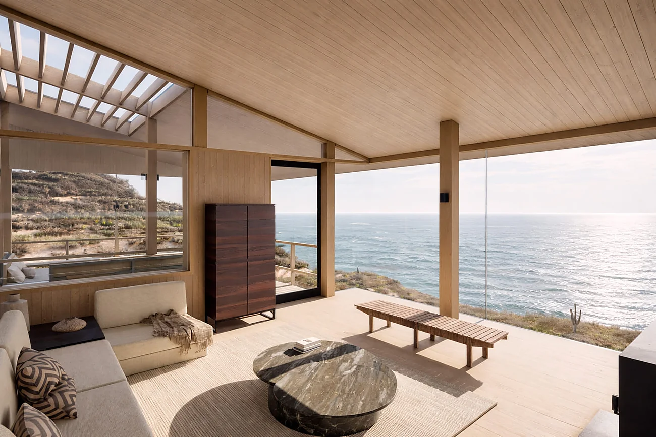 Casa KB — living con cielo y muros de madera, abierto al océano tras el ventanal