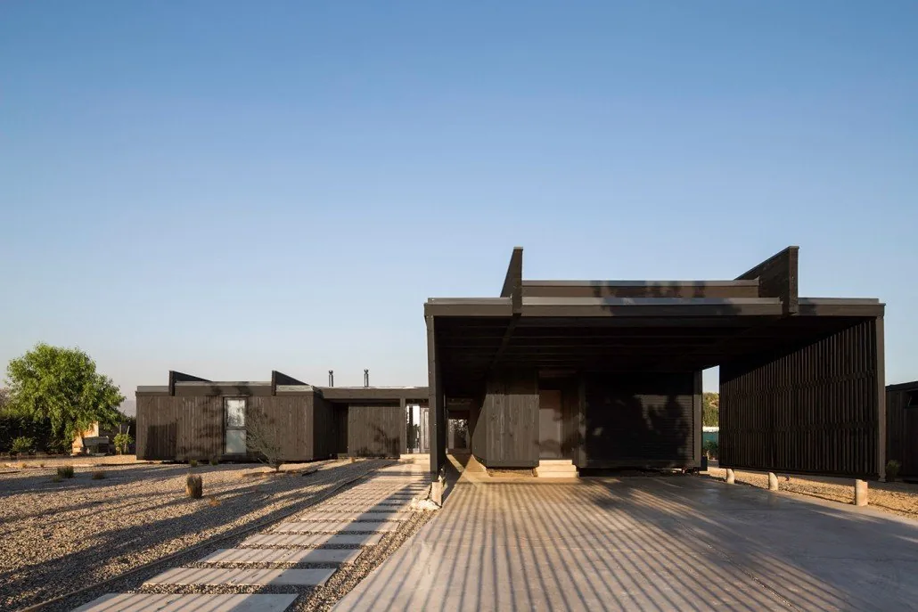 Casa TH — acceso vehicular y carport bajo la estructura de madera