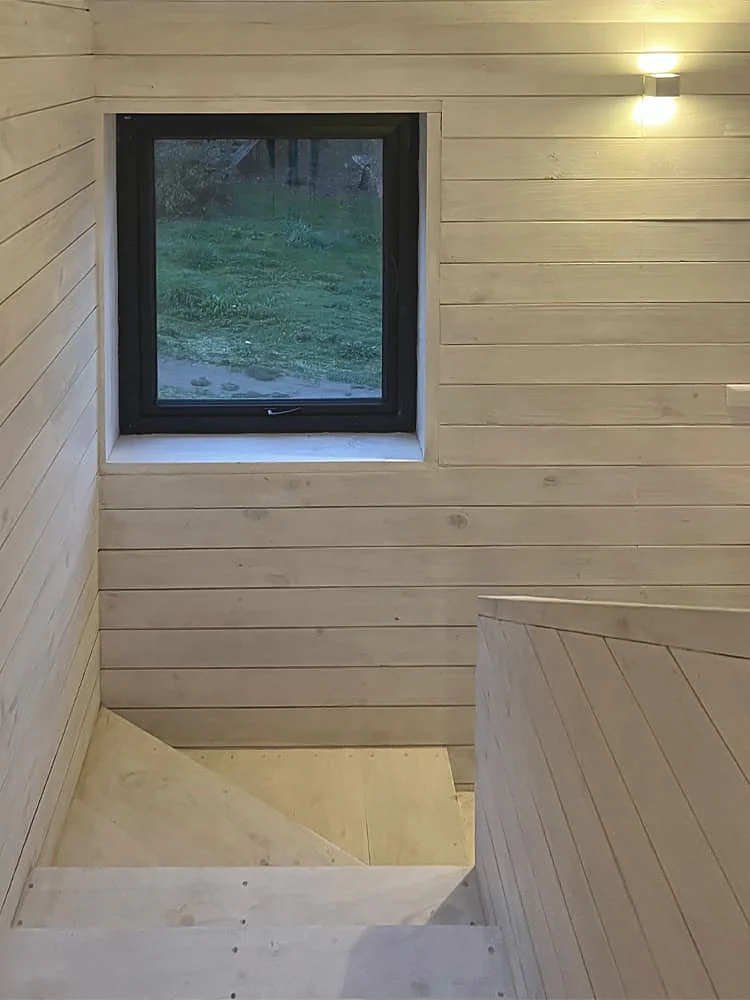 Casa VG — escalera interior con ventana hacia el jardín