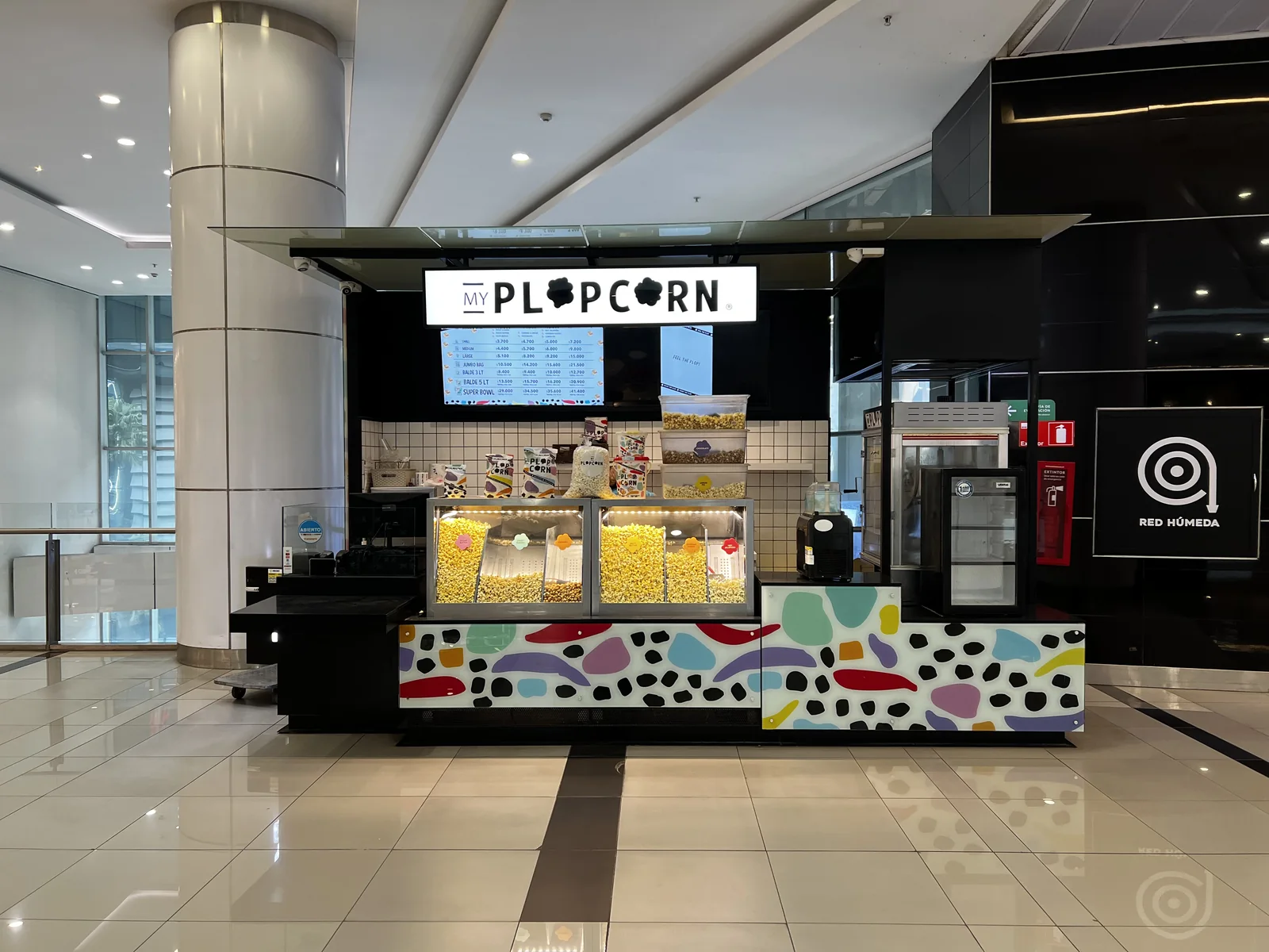 Plop Corn — módulo terminado con letrero, vitrinas y gráficas de colores en el mall